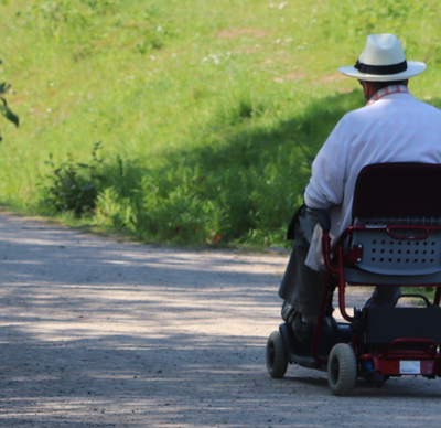 Elderly gentleman sitting in a mobility chair enjoying a view from his chair of the nature around him whilst on a footpath at Ryton pools Warwickshire on a summers morning