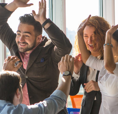 A group of business people giving high fives after dealing and signing contract or agreement with partners. Colleagues showing team work in office interior.