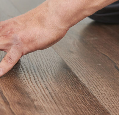 worker joining hands laying a wooden panel vinyl floor covering at home renovation