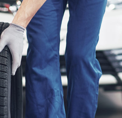 Mechanic holding a tire tire at the repair garage. replacement of winter and summer tyres